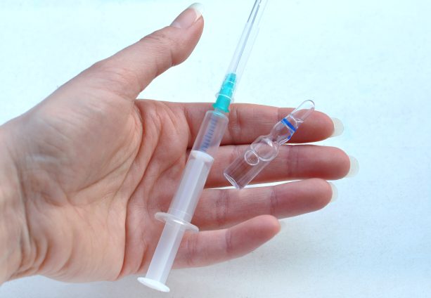 Hand holding a syringe and injection liquid