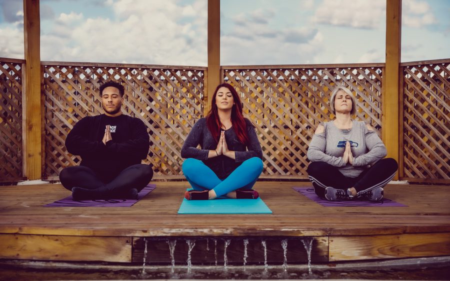 Zoomed in image of three people practicing yoga outside