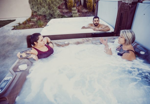 Three people talking in two different hot tubs
