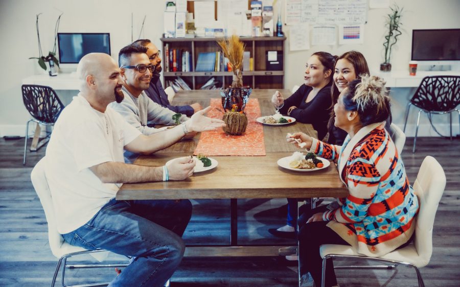 Group of people sharing a meal at a large dining table while talking and laughing