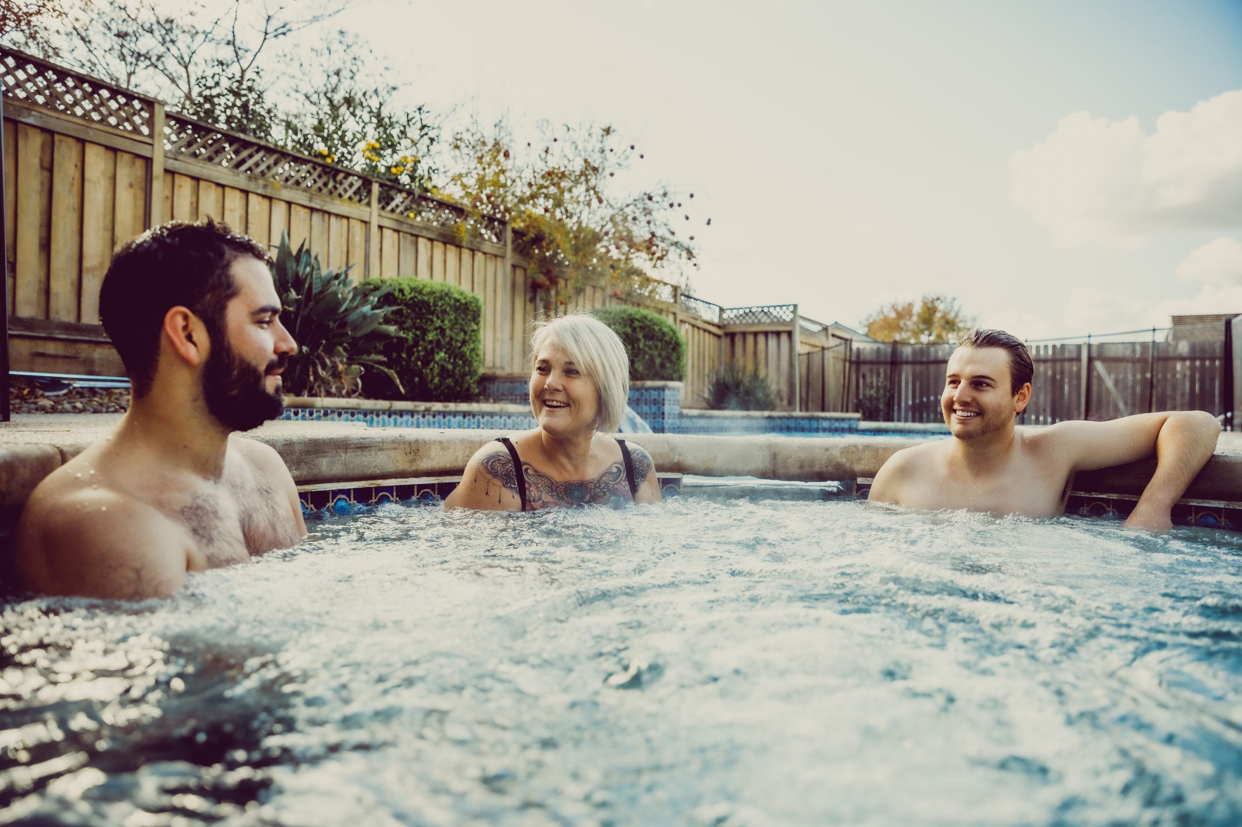 Three people talking and smiling in a hot tub