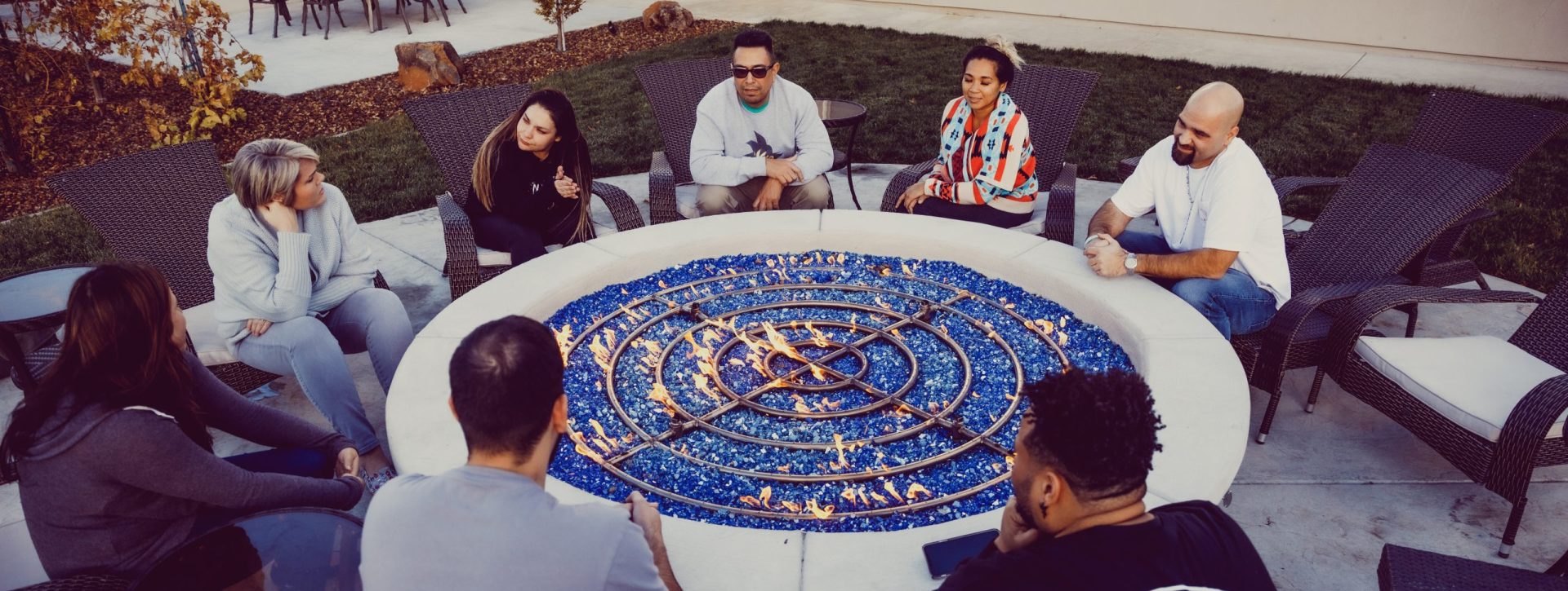 A group of people talking while sitting around a Fire Pit