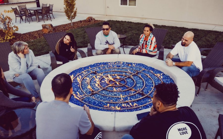 A group of people talking while sitting around a Fire Pit